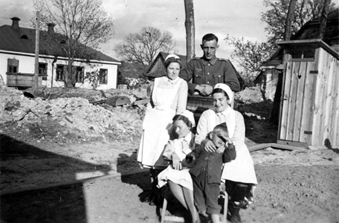 Аннетта Шюкінг (тримає українського хлопчика), ­«сестри» Лілі та Ірена, унтер-офіцер Шмідт на подвір’ї одного з будинків Звягеля в 1942 р.