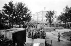Колона військовополонених на території «Морсь­кого» ру­хається з залізничної станції до концтабору в СШ №2 (імовірно на фото 3-х поверхове приміщення колишнього штабу, а нині — коледж)